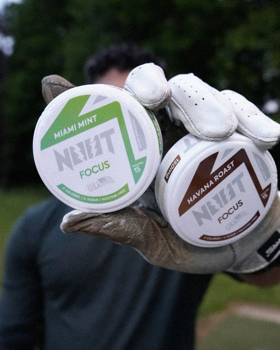 Golf glove holding a Miami Mint and a Havana Roast tin at the driving range
