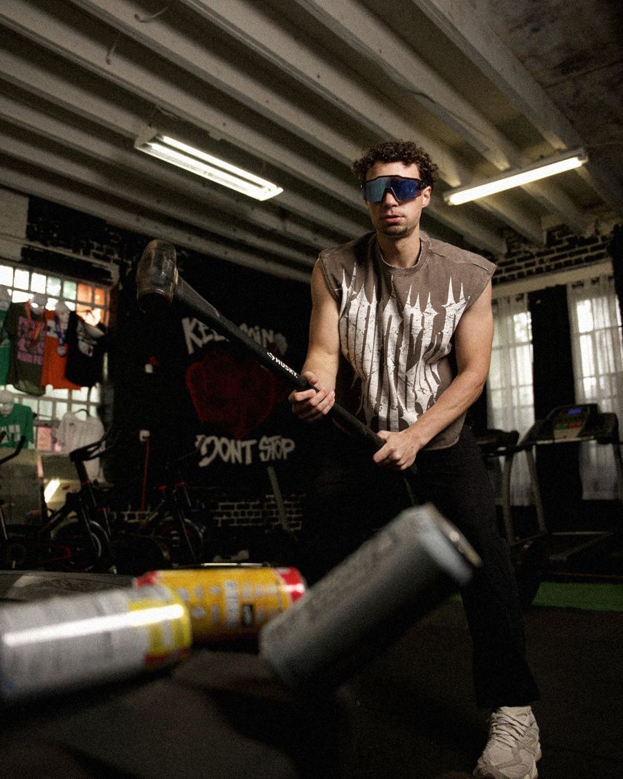 Guy in a gym swinging a sledgehammer through a row of energy drink cans